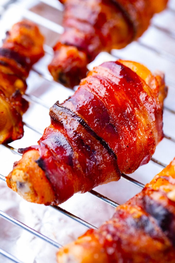 Glossy and crispy brown sugar bacon wrapped chicken drumsticks.
