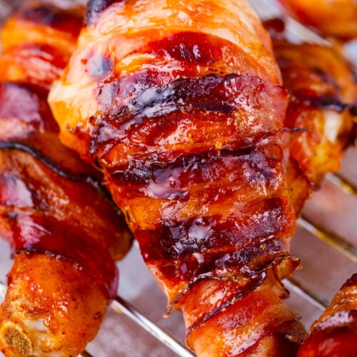 A stack of brown sugar bacon wrapped chicken drumsticks on a wire rack.