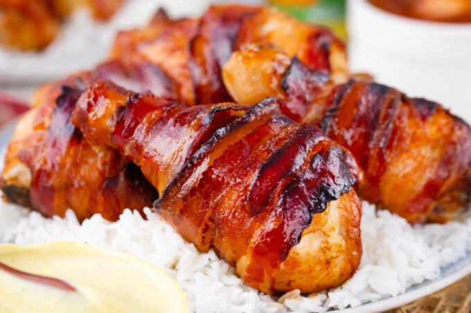 Crispy brown sugar bacon wrapped chicken drumsticks over rice.