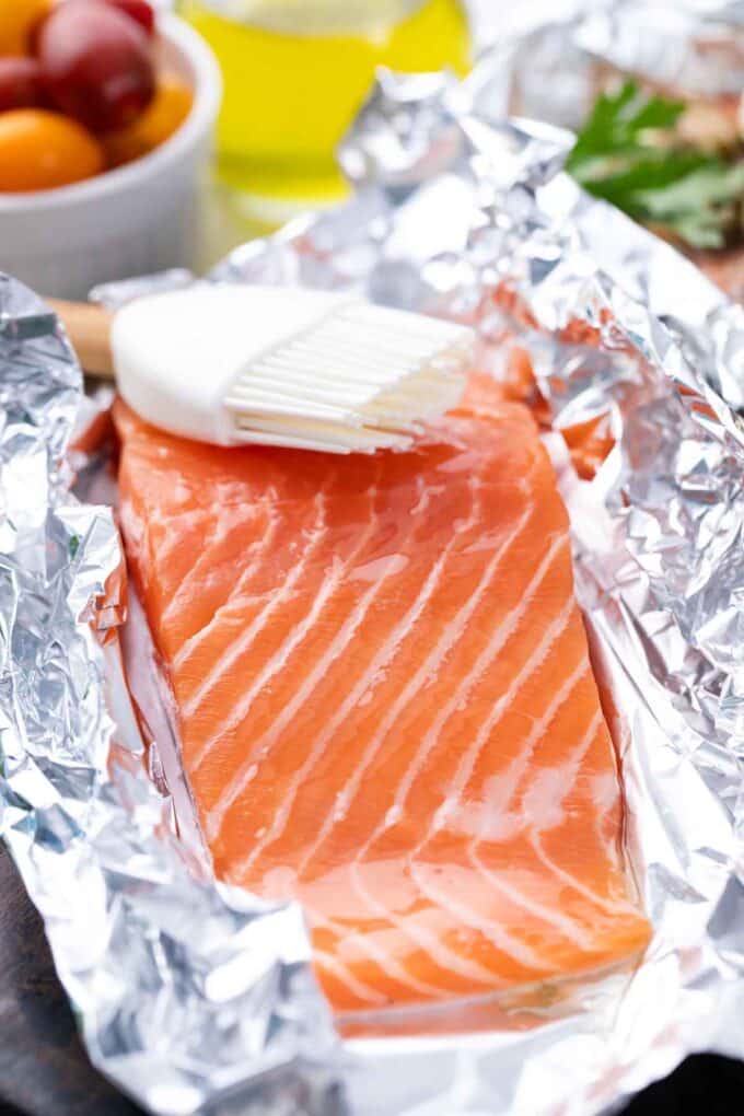 Brushing a salmon fillet in a foil packet with olive oil