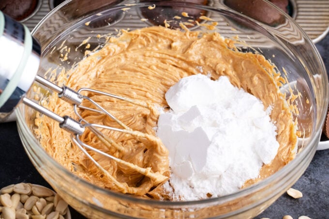 Adding powdered sugar to peanut butter frosting.