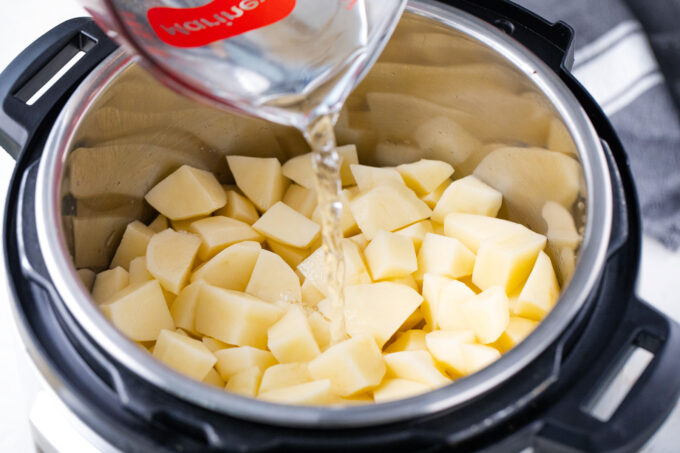 Pouring water over potatoes in the Instant Pot.