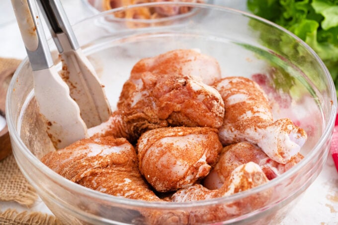 Coating chicken drumsticks in seasonig.