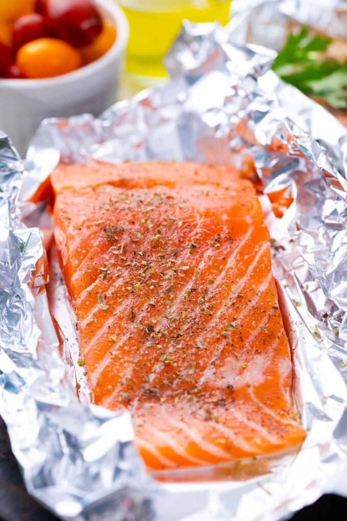 Seasoning a salmon fillet in a foil packet with salt and pepper