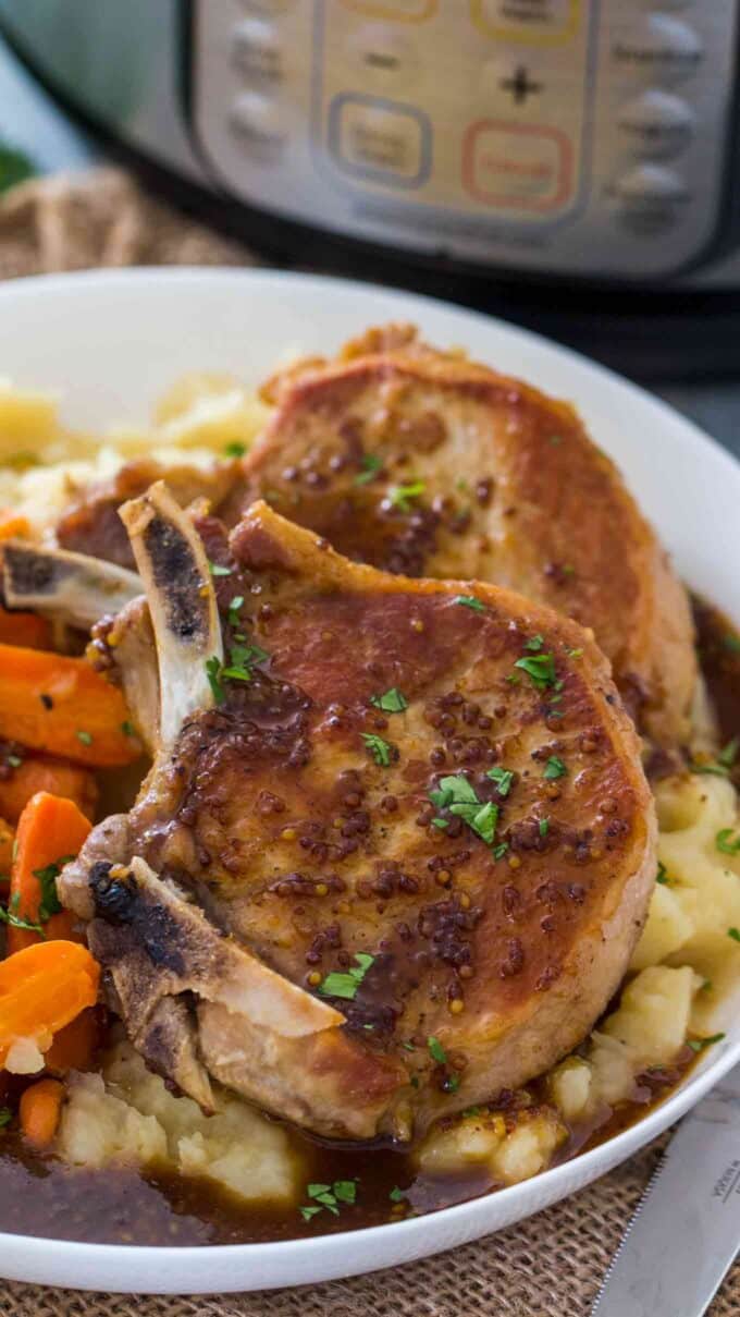 Photo of instant pot apple cider pork chops over mashed potatoes.