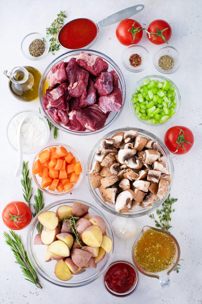 Overhead shot of Instant Pot beef Bourguignon ingredients in bowls on a white surface.