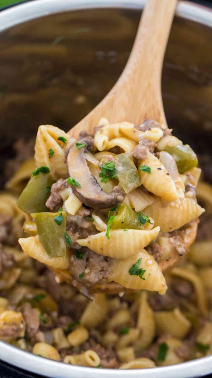 a wound spoon filled with instant pot Philly cheesesteak pasta garnished with chopped parsley