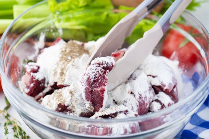 Coating cubed beef pieces in flour, salt, and pepper.