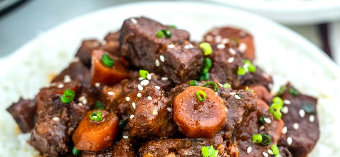 Image of slow cooker beef teriyaki garnished with sesame seeds over white rice.