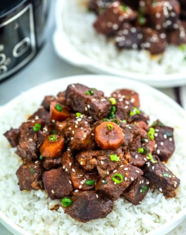 Image of slow cooker beef teriyaki garnished with sesame seeds over white rice.