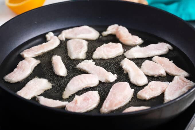 Frying chicken pieces in a pan.
