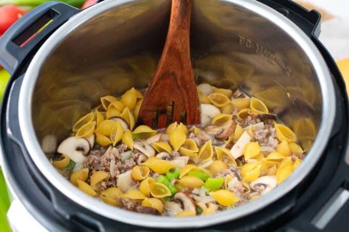 mixing instant pot philly cheesesteak pasta ingredients in the pot