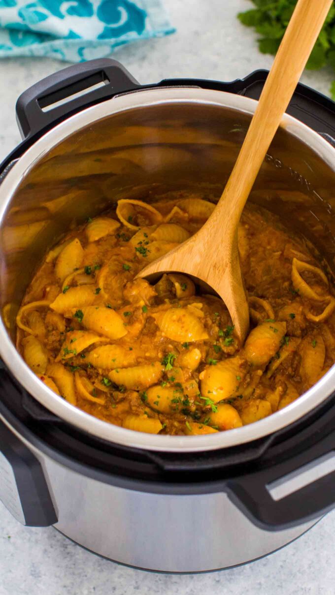 instant pot taco pasta in the pressure cooker with a stirring wooden spoon in it