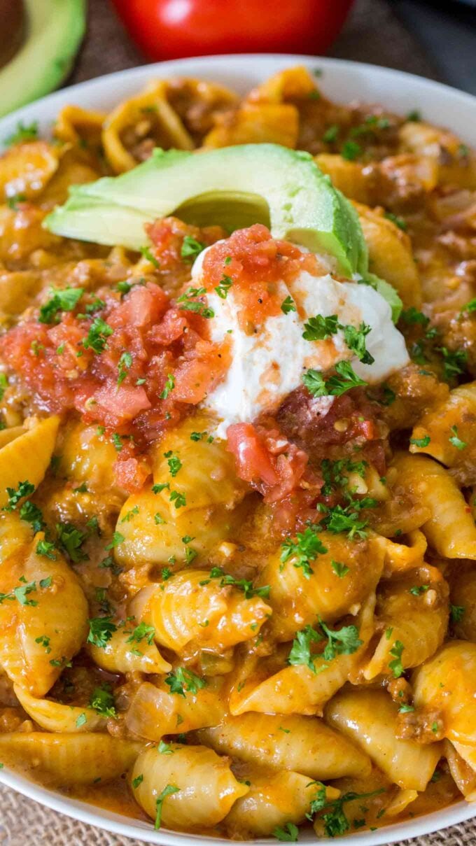 taco pasta topped with sour cream, salsa and avocado