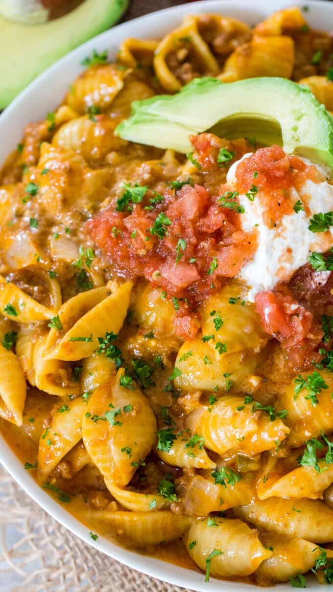 Beef taco pasta garnished with sliced avocado and sour cream