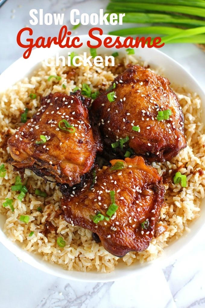 Crispy Slow Cooker Garlic Sesame Chicken over rice topped with green onions and sesame seeds