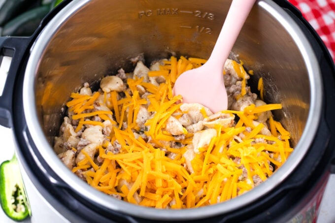 Adding cheddar cheese to instant pot jalapeno popper pasta.