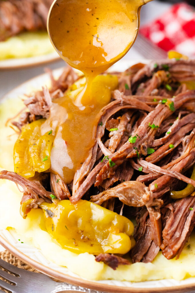 Drizzling gravy over instant pot Mississippi pot roast.