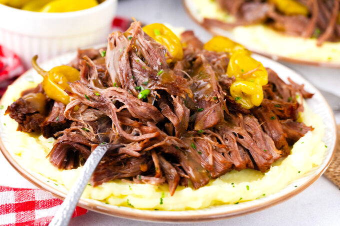 Succulent instant pot Mississippi pot roast with pepperoncini over mashed potatoes.