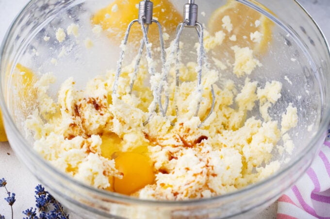 Beating butter, sugar, and eggs in a bowl.