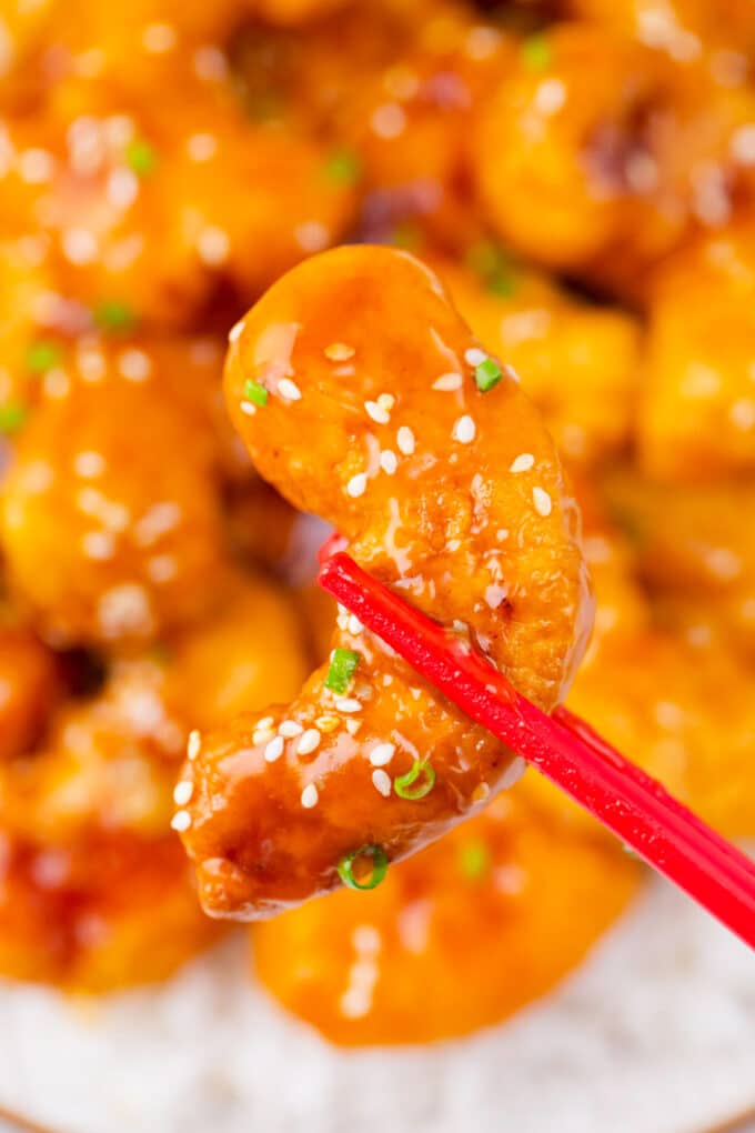Holding PF Chang's crispy honey shrimp with chopsticks.