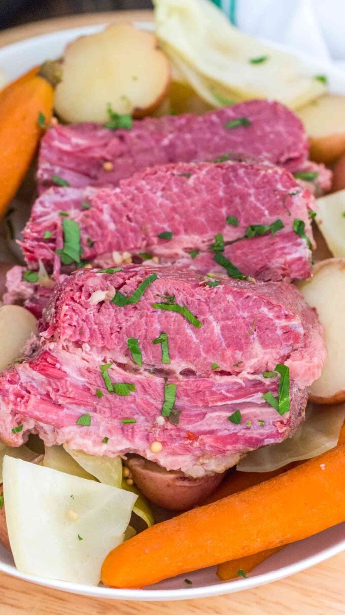 Cut crockpot corned beef with cabbage potatoes and carrots on a plate