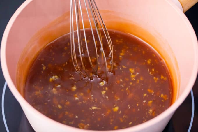 Whisking honey garlic sauce in a saucepan.