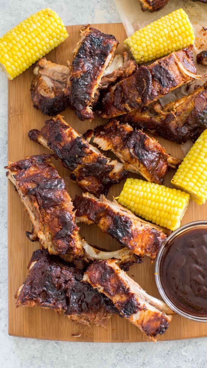 sliced instant pot pork ribs glazed with barbecue sauce and cooked corn on a serving board