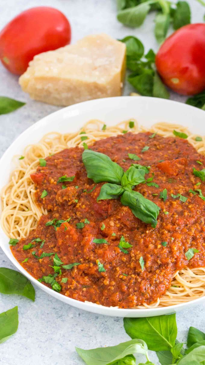 spaghetti sauce over pasta garnished with fresh basil
