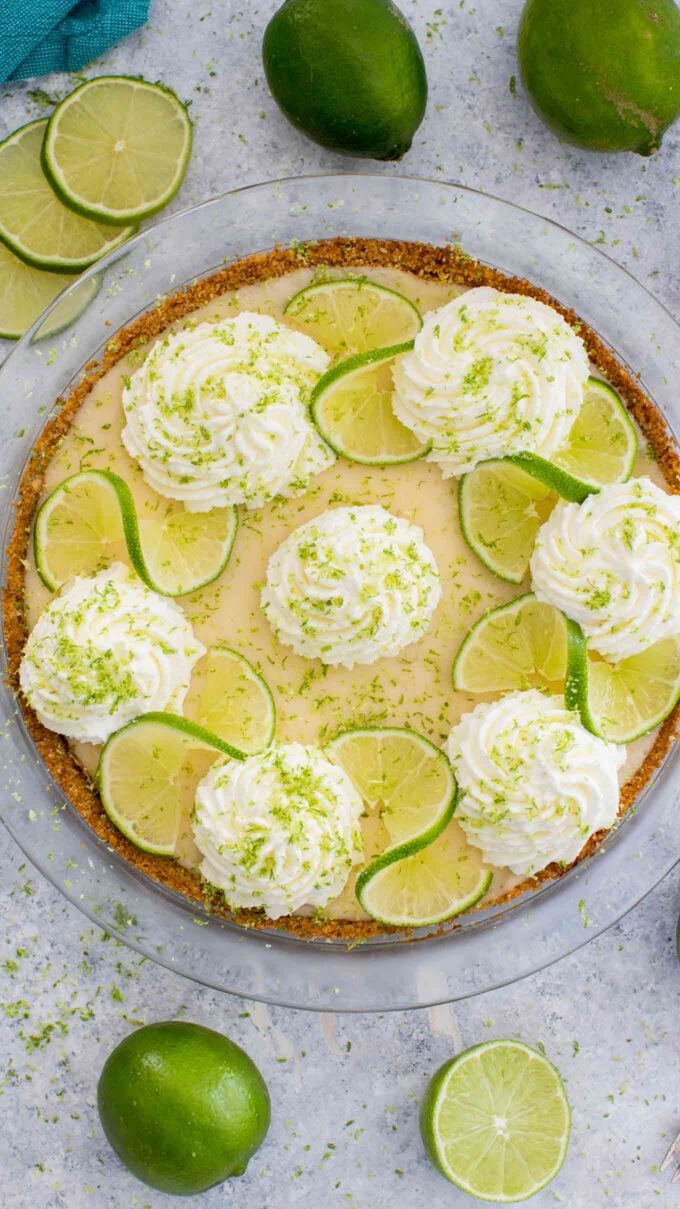 overhead shot of homemade key lime pie topped with whipped cream lime zest and lime slices
