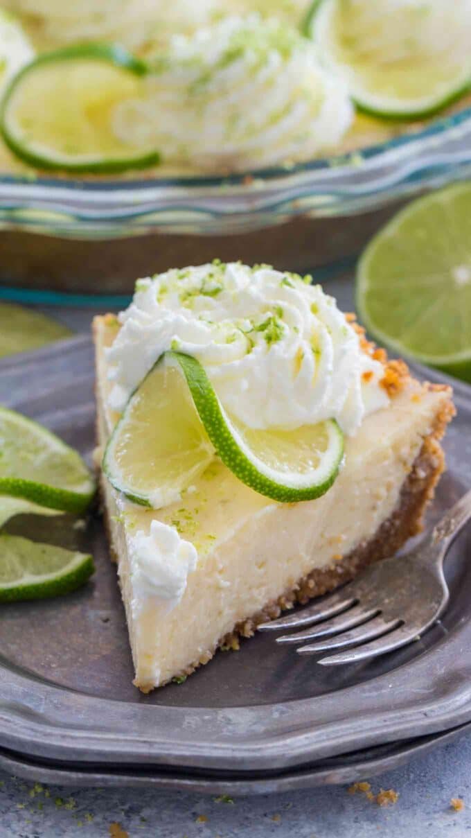 a slice of key lime pie topped with whipped cream and lime slices