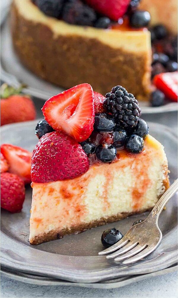 A slice of classic instant pot cheesecake topped with berries in a jam sauce.