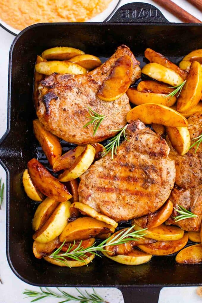 apple cinnamon pork chops recipe with fresh rosemary in a cast iron skillet