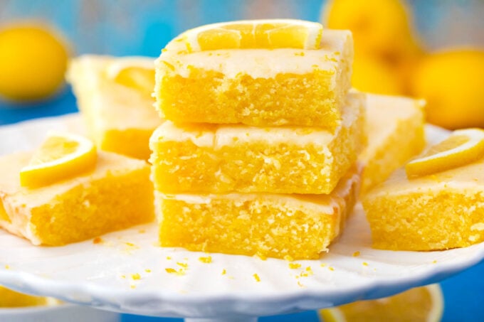 A stack of fudgy lemon brownies on a cake stand.