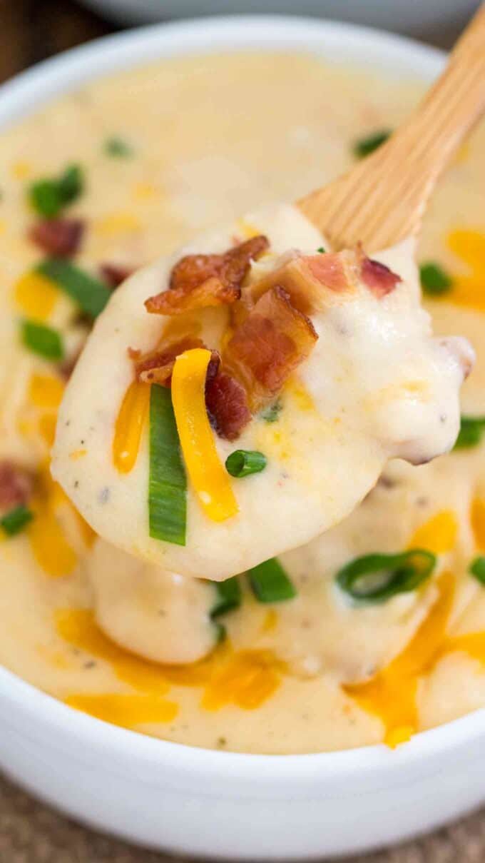 a spoonful of baked potato soup in a white bowl