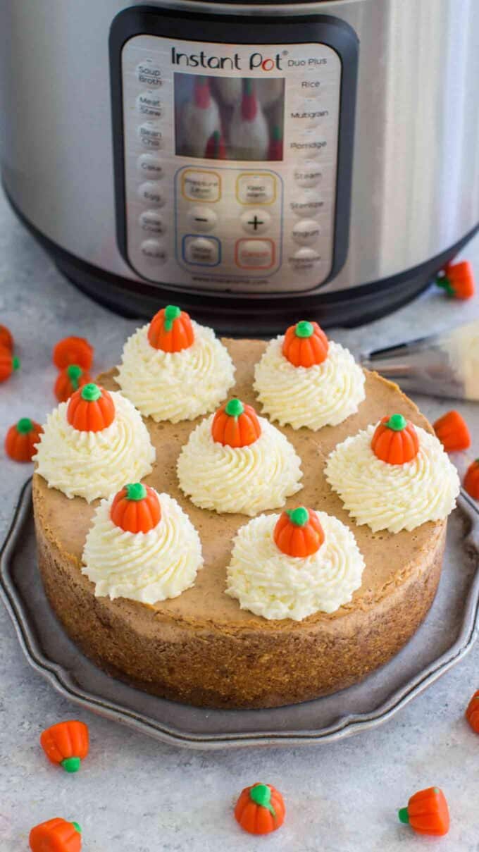 instant pot pumpkin cheesecake topped with whipped cream and pumpkin candies