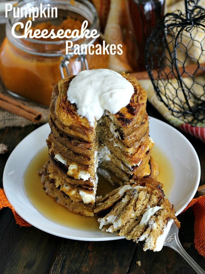 Fluffy and flavorful Pumpkin pancakes on a white plate topped with whipped cream and maple syrup