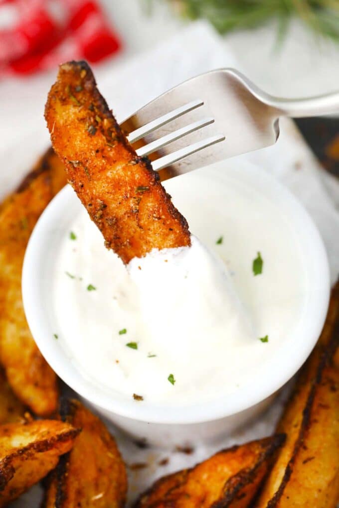 dipping a crispy roasted rosemary potato in a white sauce