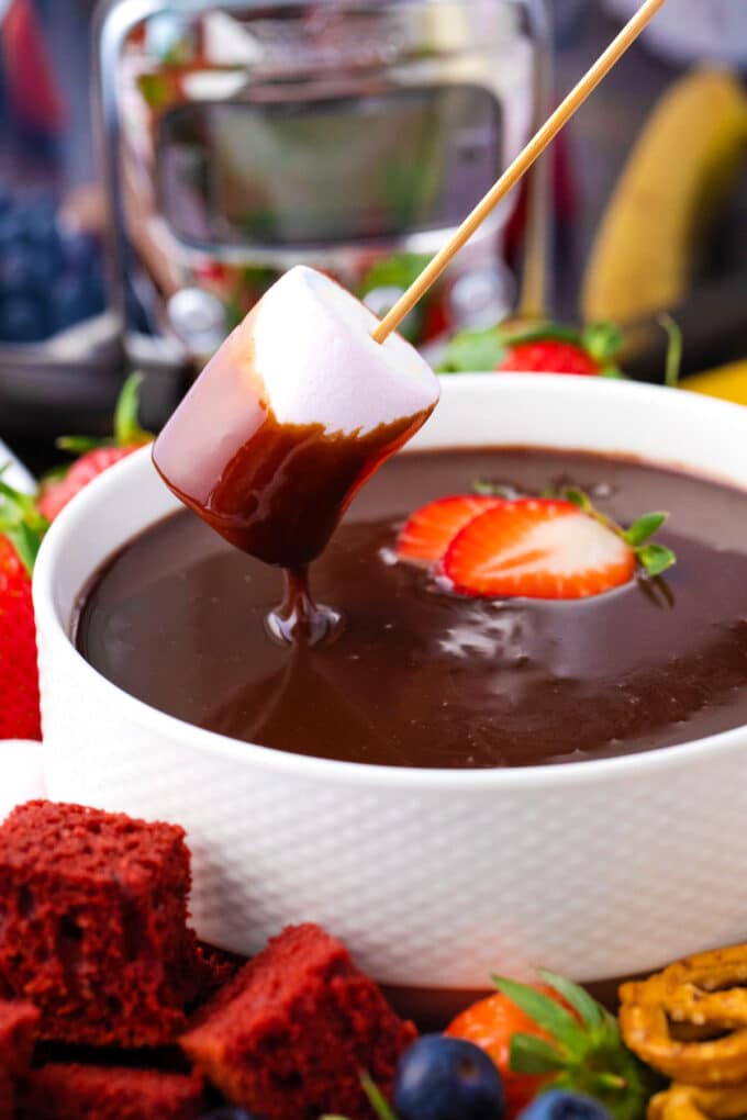 Dipping a marshmallow in slow cooker chocolate fondue.