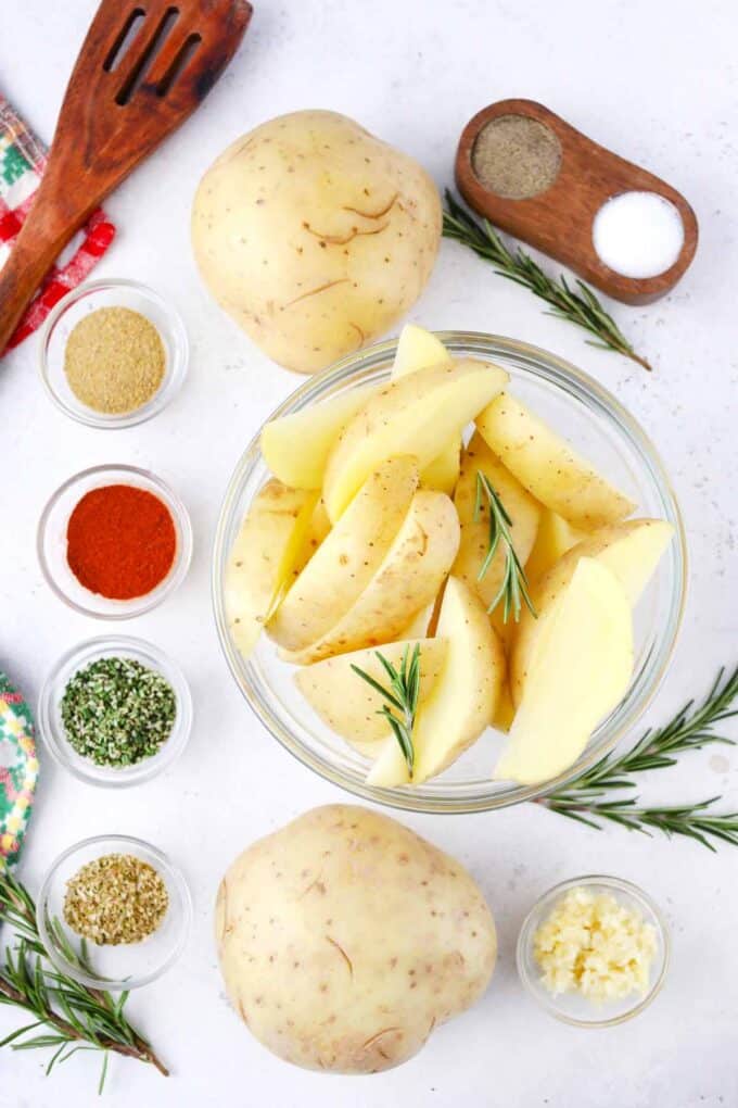 crispy roasted rosemary potatoes ingredients in bowls on a white surface