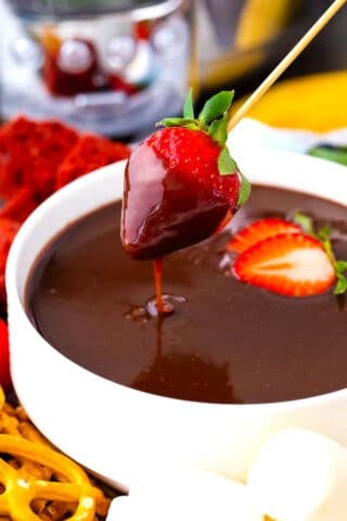 Dipping a strawberry in crockpot chocolate fondue.