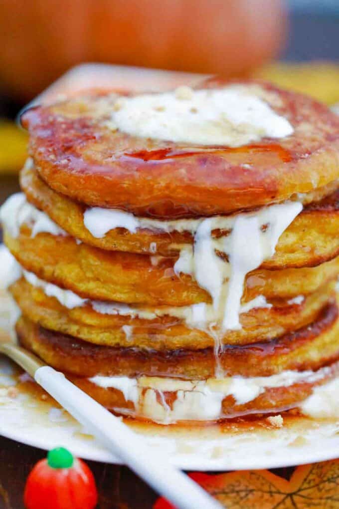 stack of pumpkin cheesecake pancakes with melted cream cheese