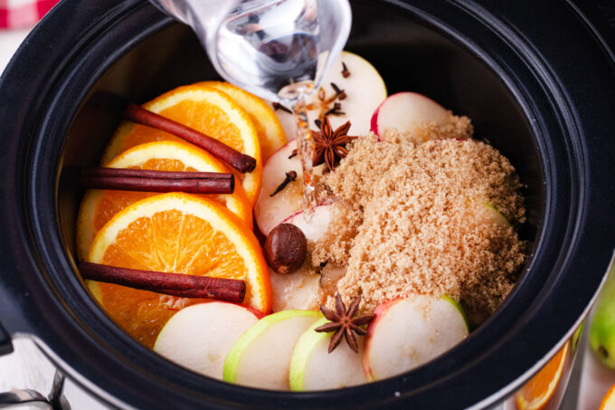 Adding slow cooker apple cider ingredients to the slow cooker.