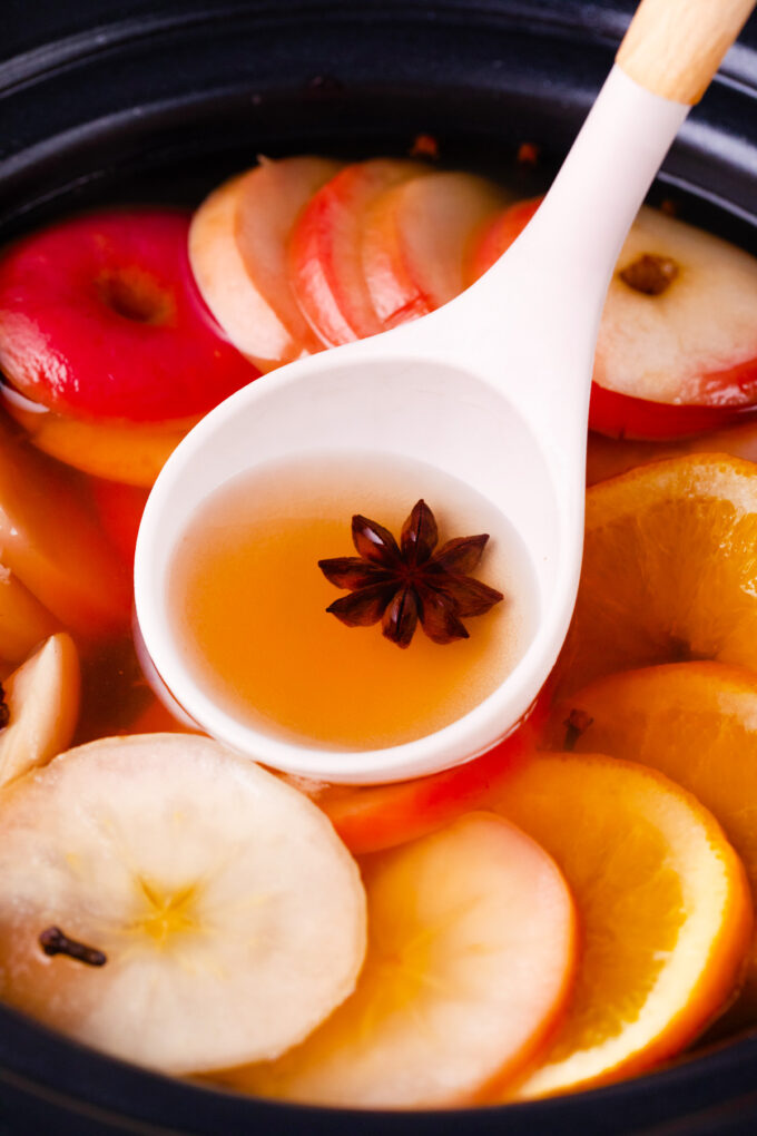 A ladle of spiced slow cooker apple cider.
