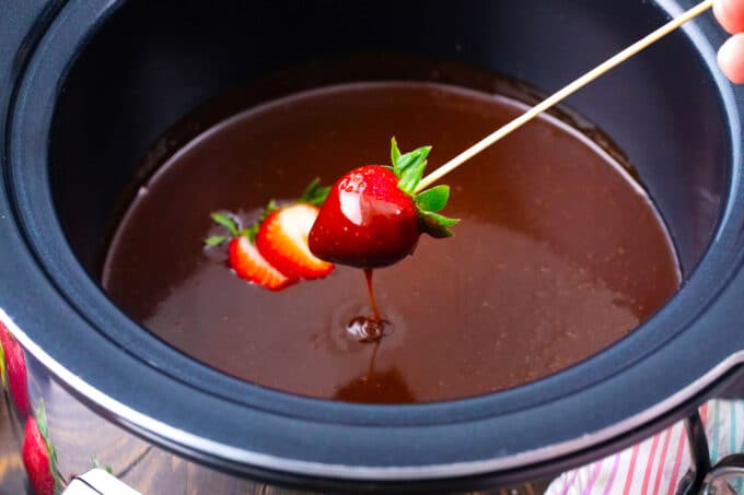Dipping a strawberry into crockpot chocolate fondue.