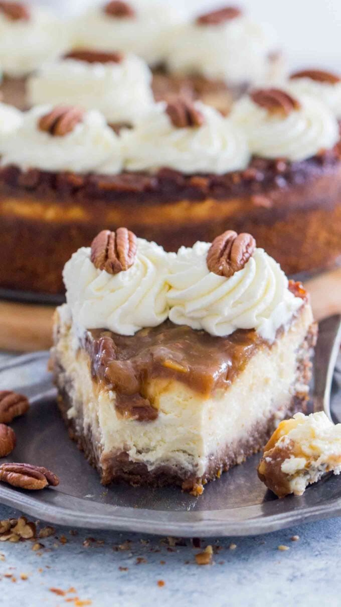 A slice of Pecan Pie Cheesecake topped with pecan pie filling