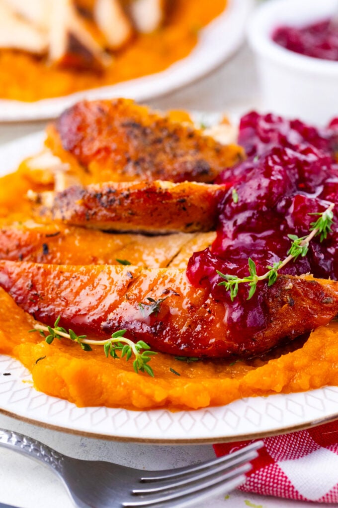 Browned instant pot turkey breast served with cranberry sauce and mashed potatoes.