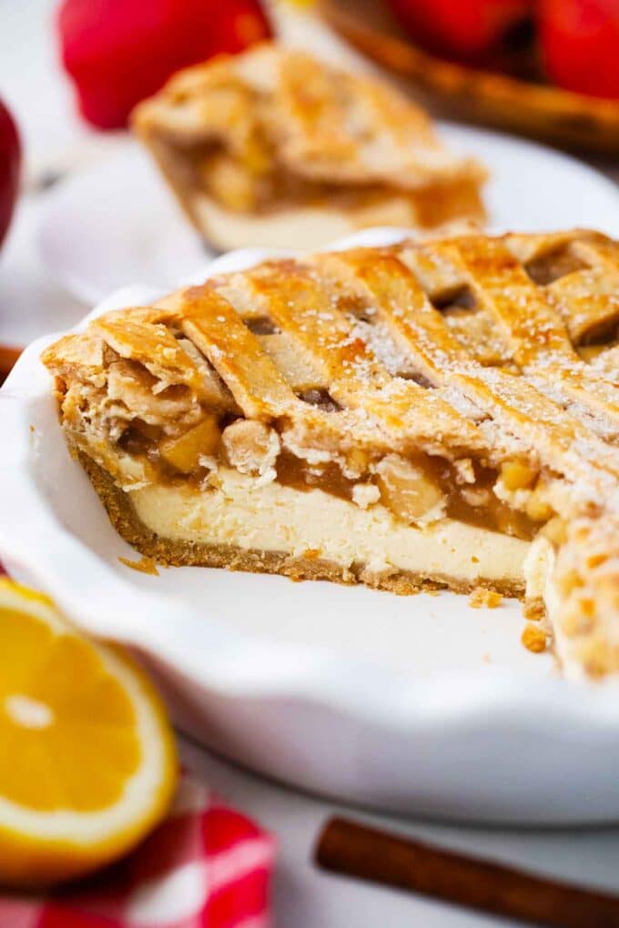 sliced apple pie in a baking pan revealing a cheesecake layer and apple pie filling