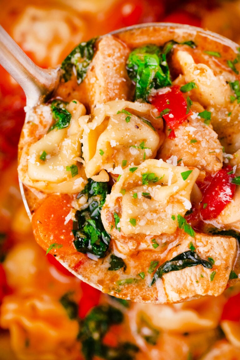 A ladle of creamy tuscan chicken tortellini soup.