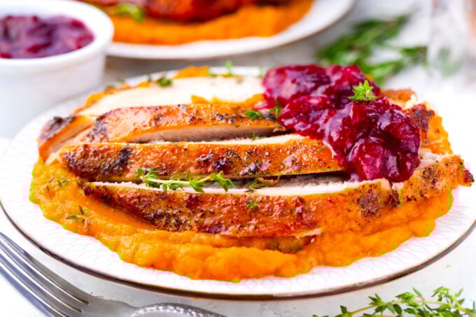 Browned Instant Pot turkey breast sliced and served with cranberry sauce and mashed sweet potatoes.